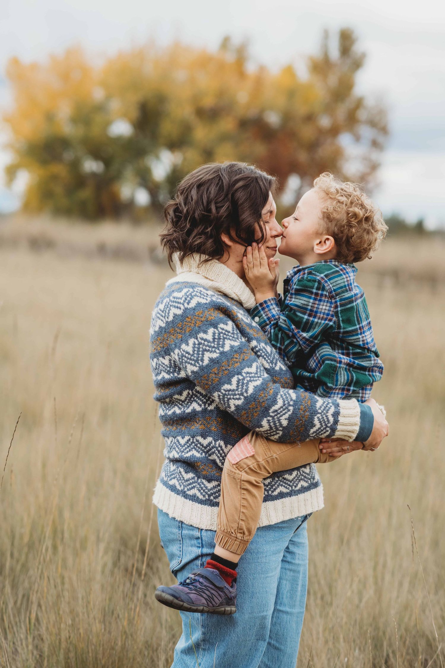 A mother holding her son while he kisses her nose.