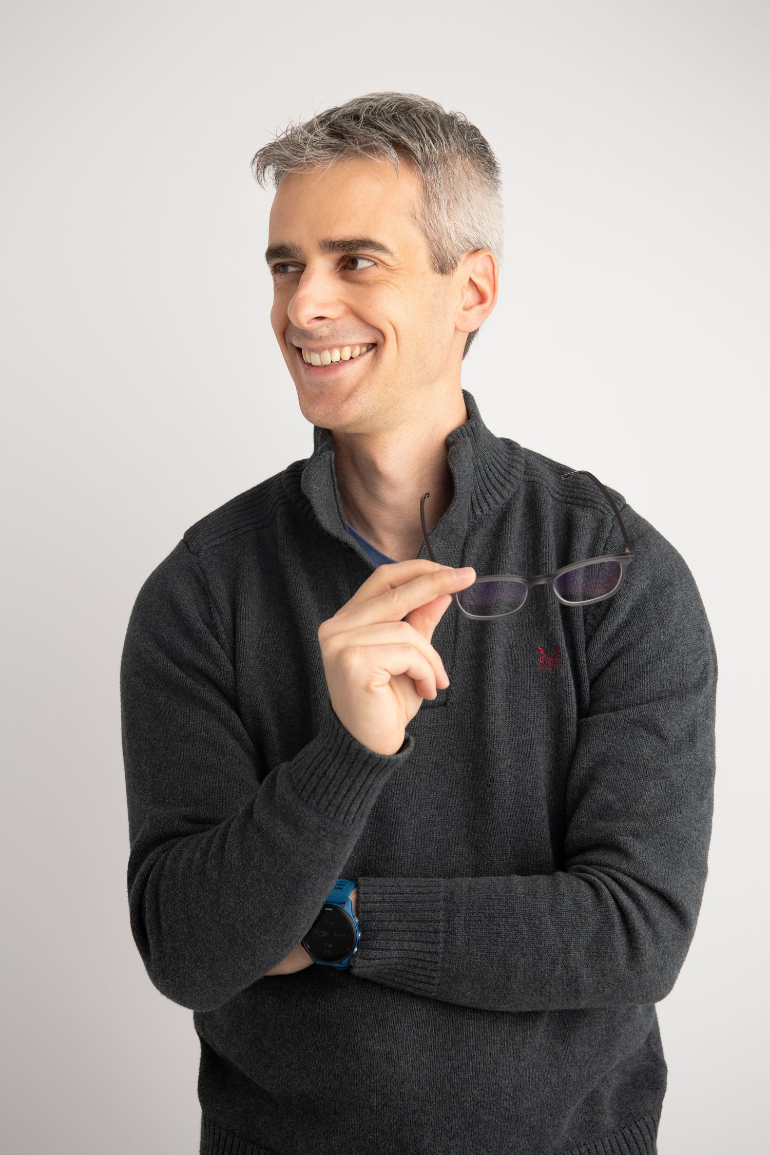 A professional business headshot of a man holding his glasses and looking away from the camera at a Walla Walla studio.