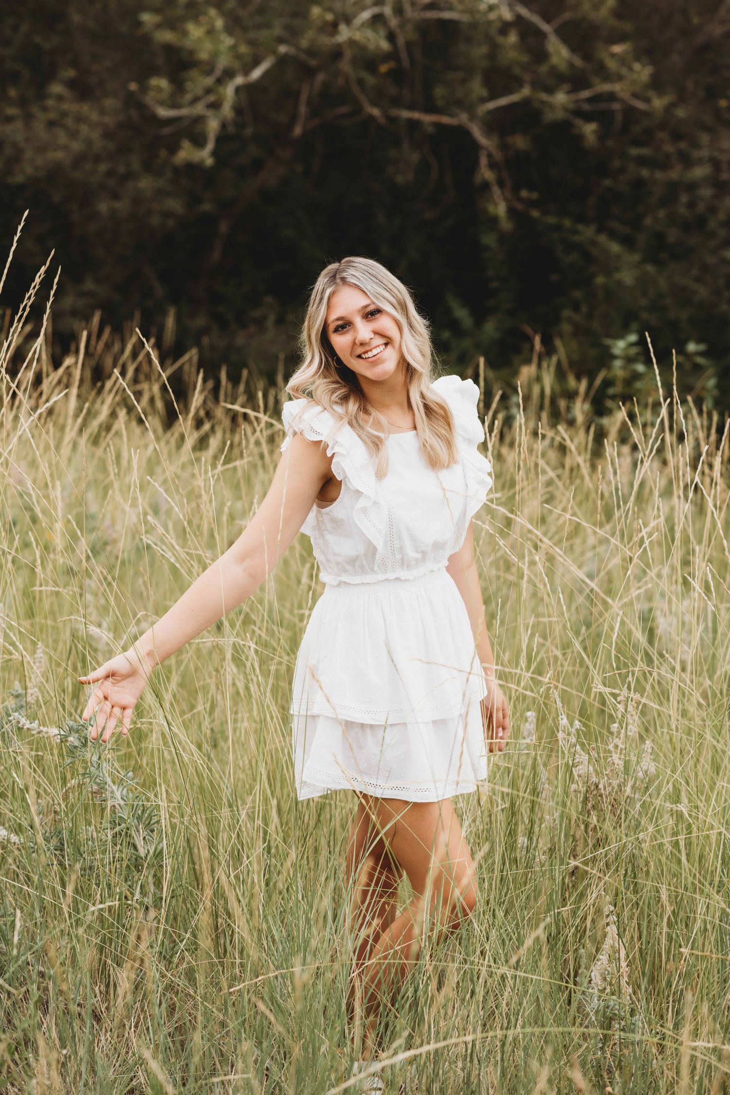 A senior running her hand through tall grasses as she walks at Bennington Lake in Walla Walla, Washington.
