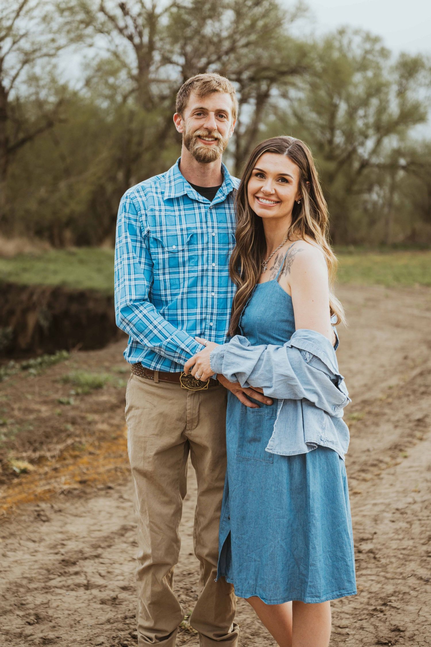 A portrait of a couple wearing blue and tan on their family farm.