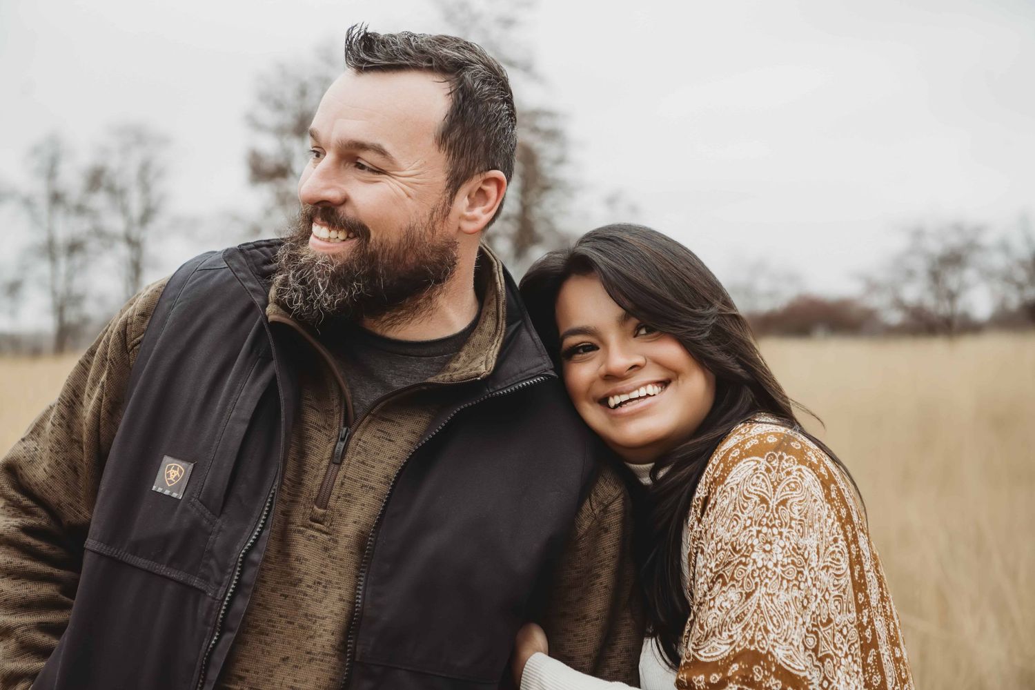 A wife leaning on her husbands shoulder as they walk through a field in Walla Walla.