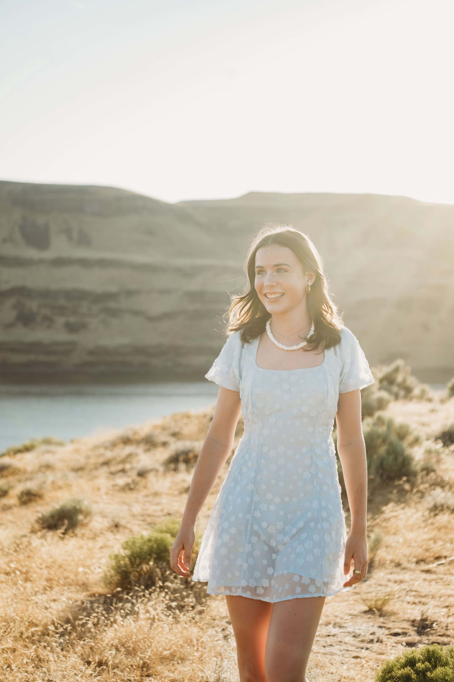 A teenage girl wearing a soft blue dress walking in golden sunshine in Walla Walla.