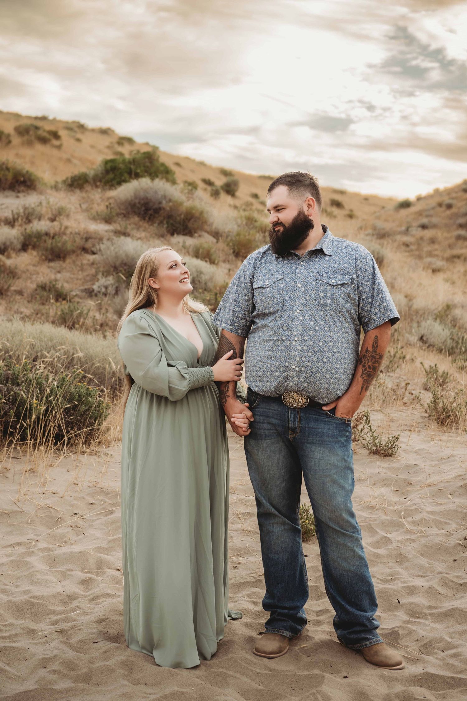 Couple holding hands and walking together through sandy terrain during a Walla Walla couples photo session.