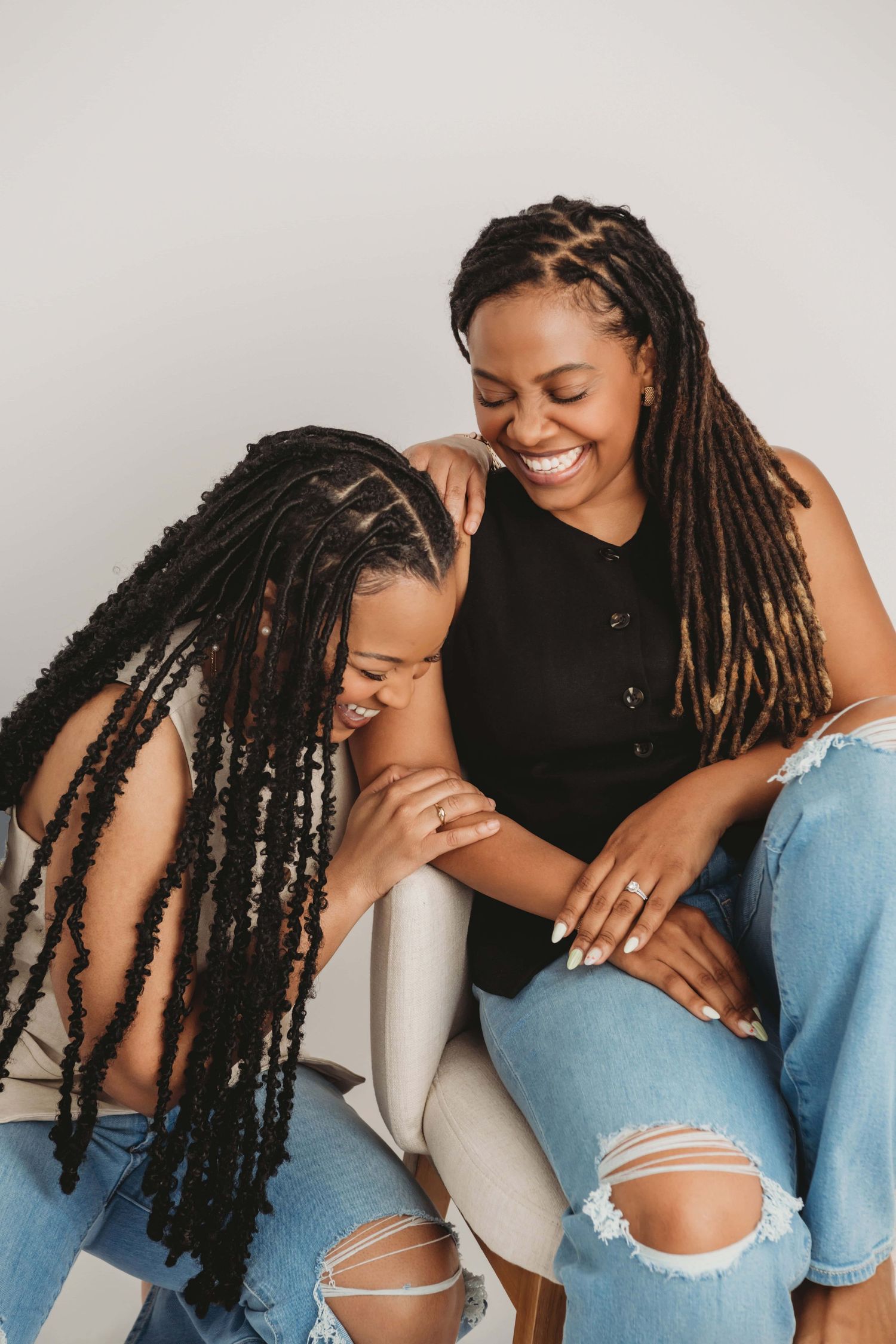 Two sisters looking at each other laughing in a studio portrait taken in Walla Walla.
