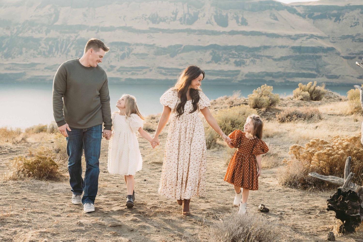 A family portrait of a family of four walking with a river and mountains in the background at Twin Sisters in Walla Walla.