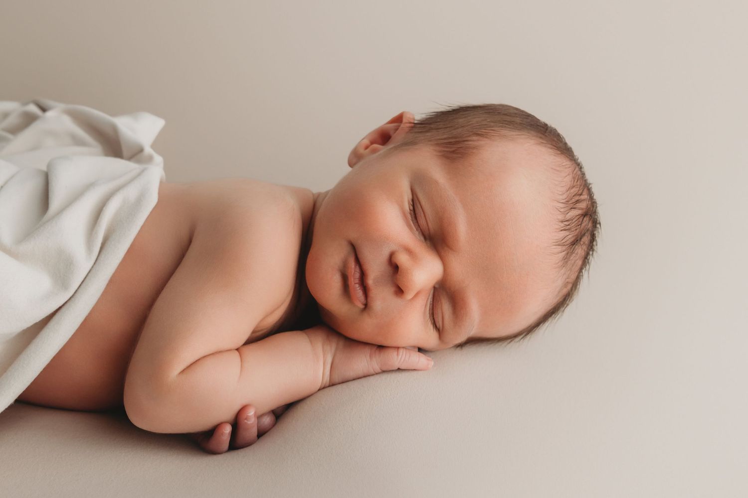 A newborn sleeping on a neutral backdrop, captured by a Walla Walla newborn photographer.