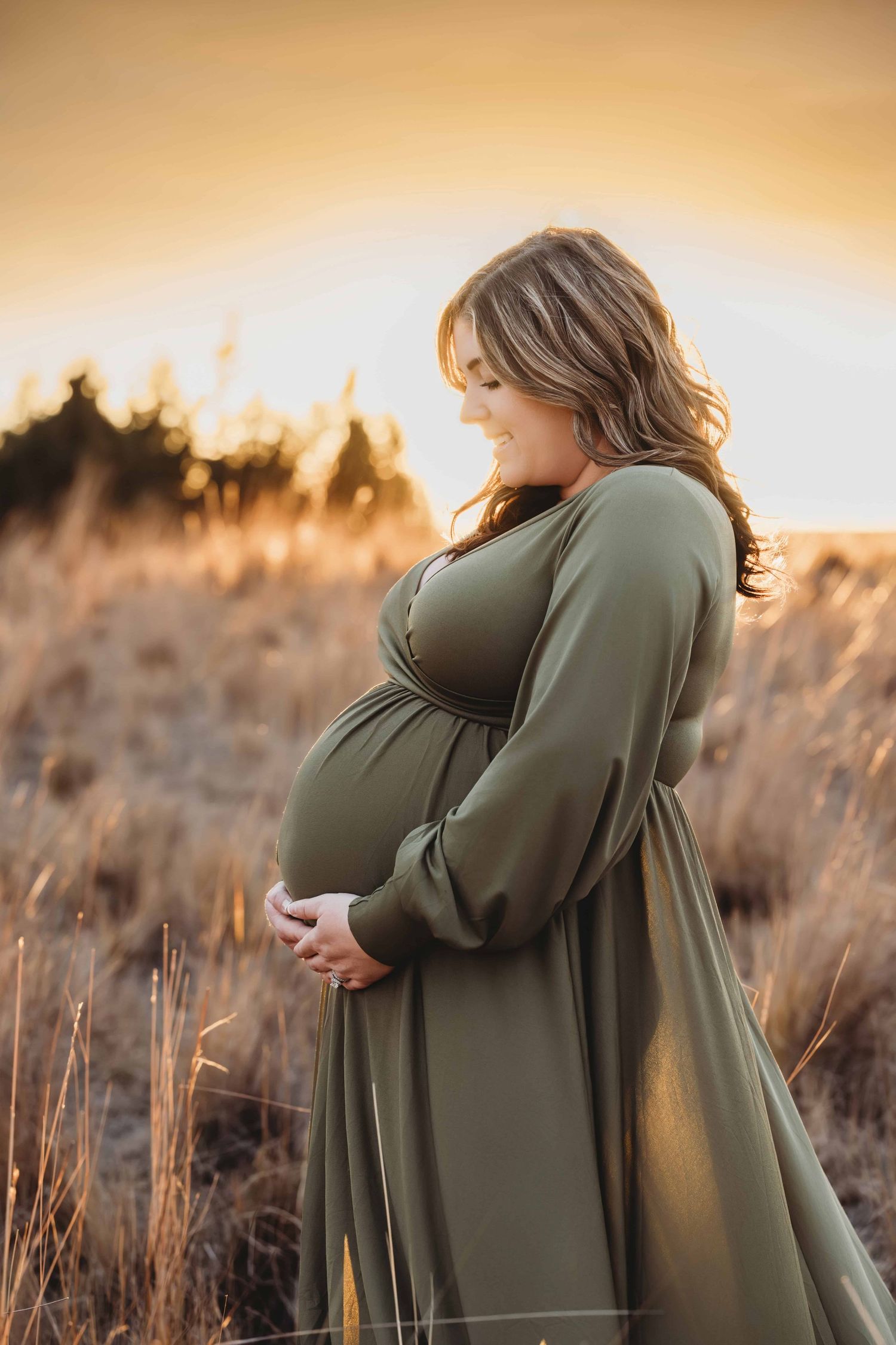 Close-up maternity photography portrait of a pregnant woman smiling down at her baby bump in Walla Walla, Washington.