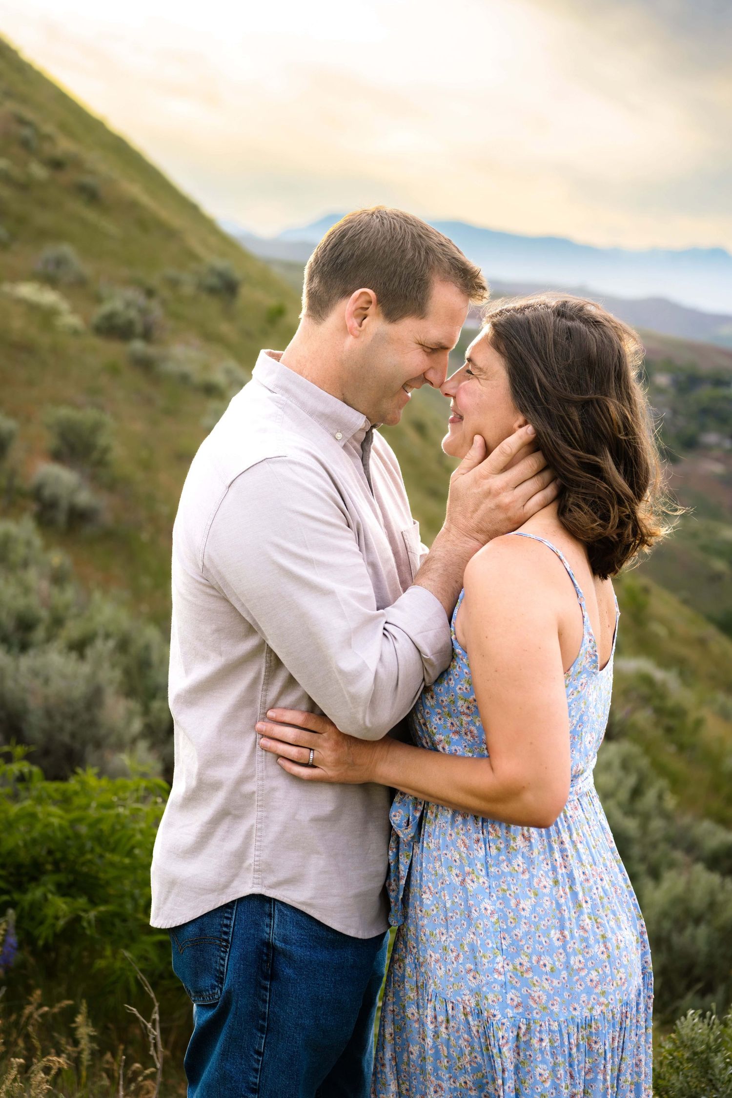 A couple intimately looking at each other smiling, with the mountains in the background in Wenatchee Washington.