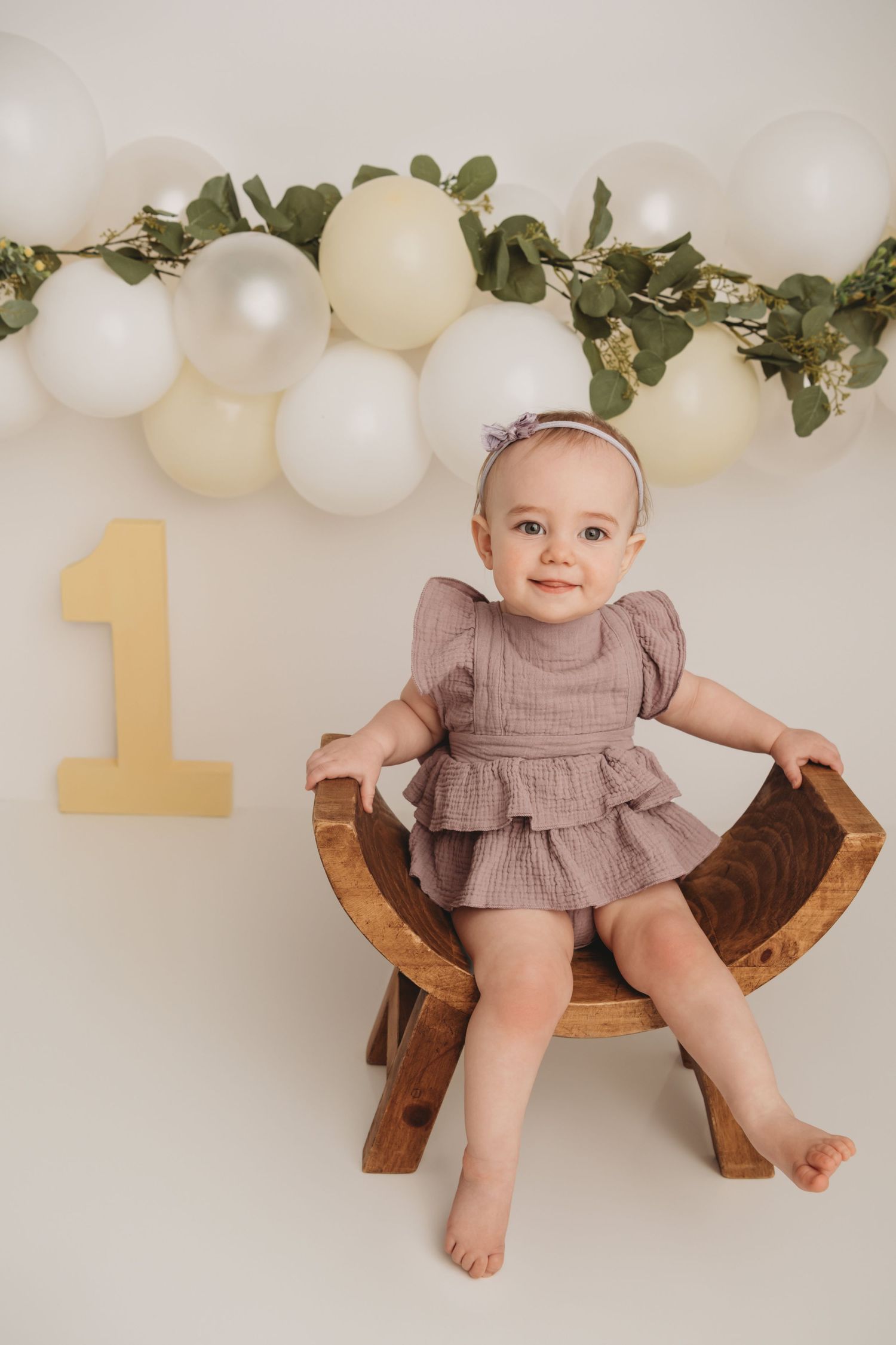 A portrait of a one year old sitting on a wooden stool with a 1 in the background at a Walla Walla photography studio.