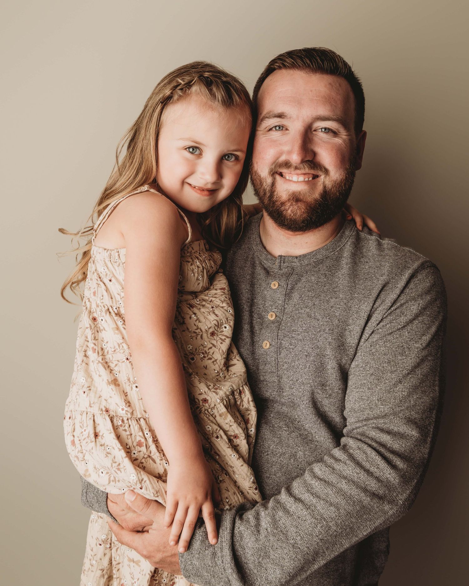 A dad holding his daughter on a neutral backdrop in a Walla Walla studio.