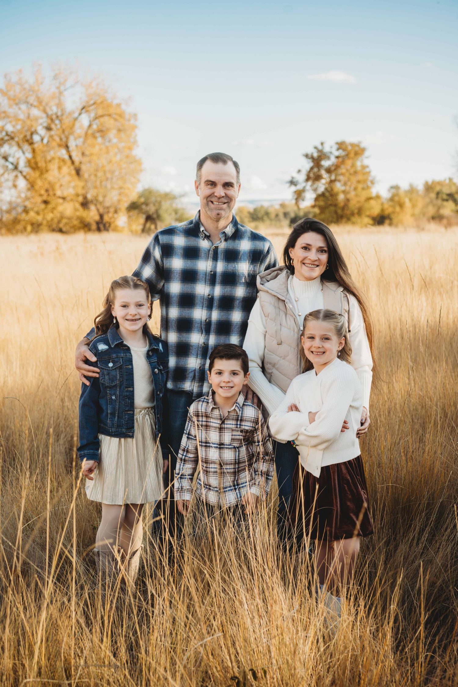 A family of five standing together with bright blue skies.