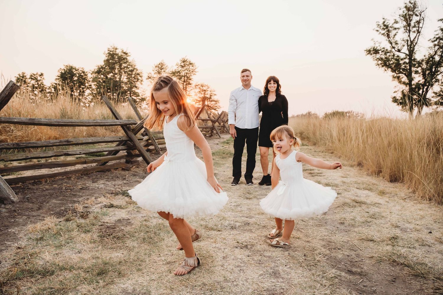 A family portrait of two girls spinning in white dresses with their parents in the background watching in Walla Walla.