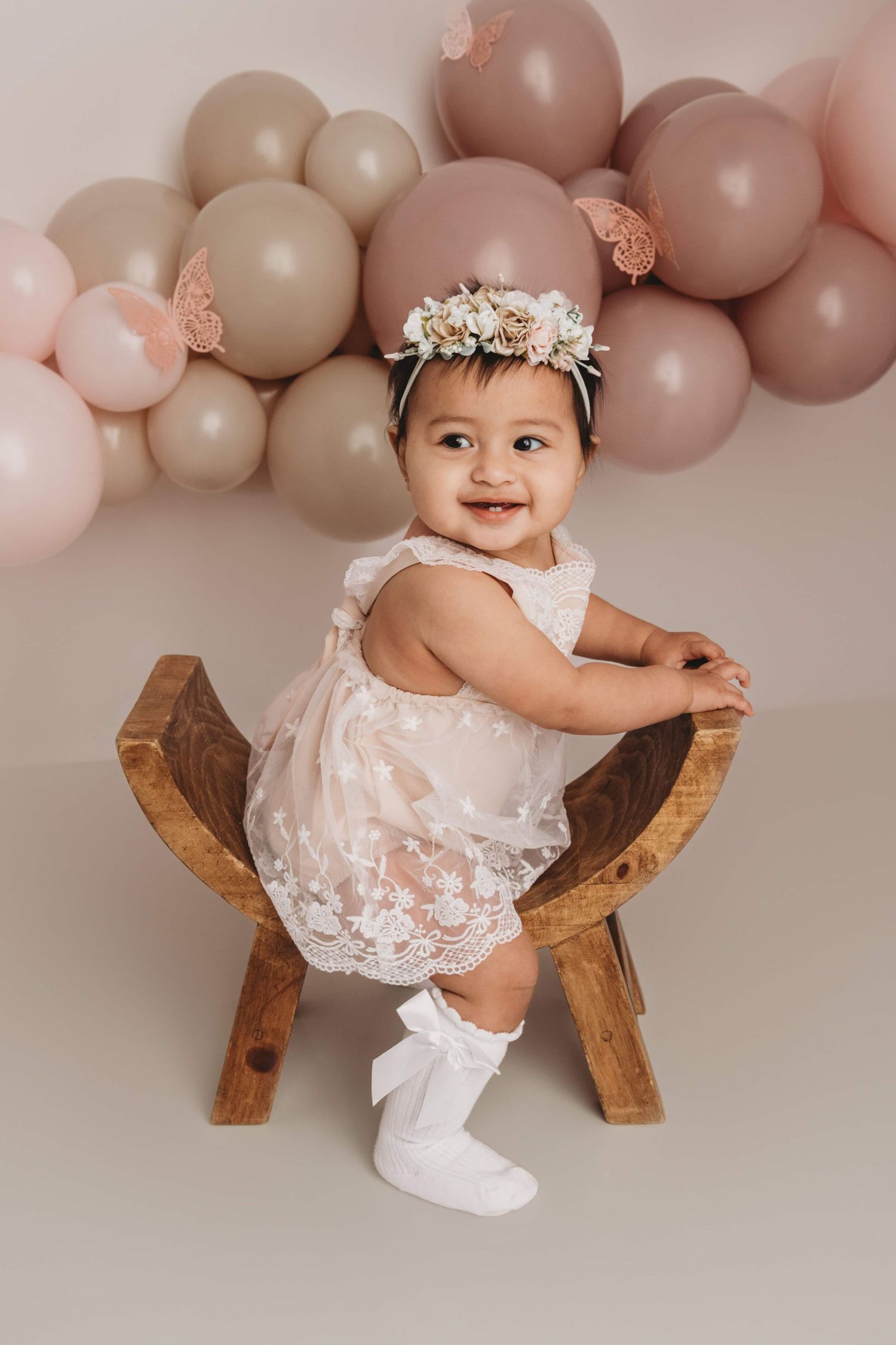 A photographer captures a one year old sitting on a wooden stool with balloons in the background at a Walla Walla studio.