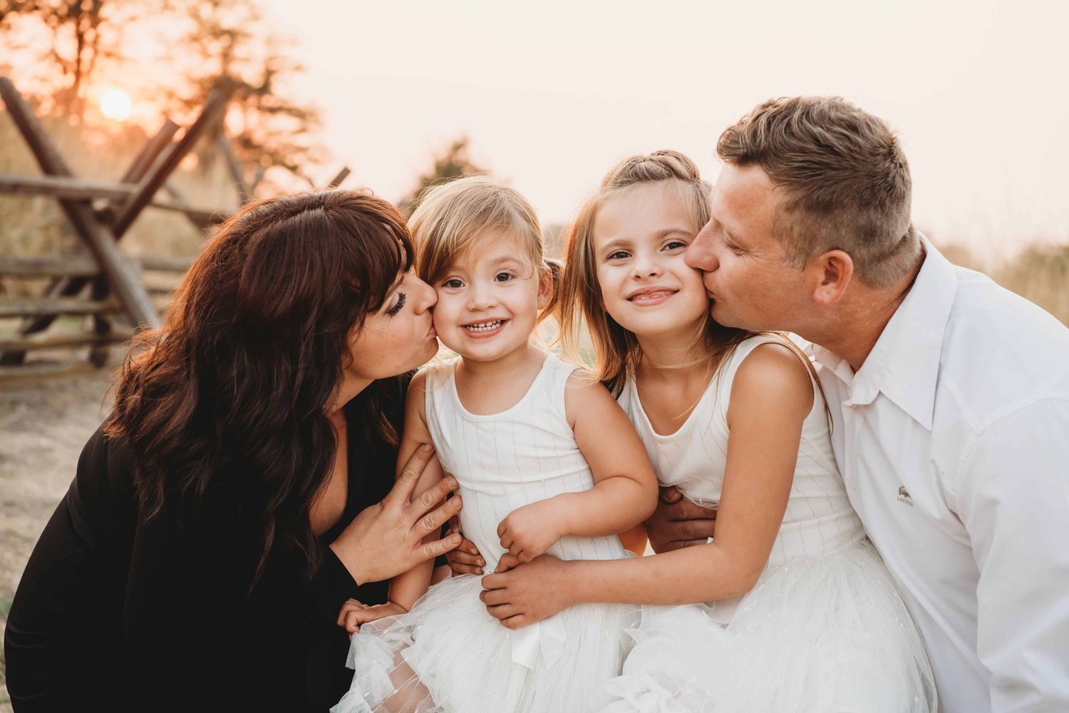 A family portrait of parents kissing their kids on the cheeks in Walla Walla.