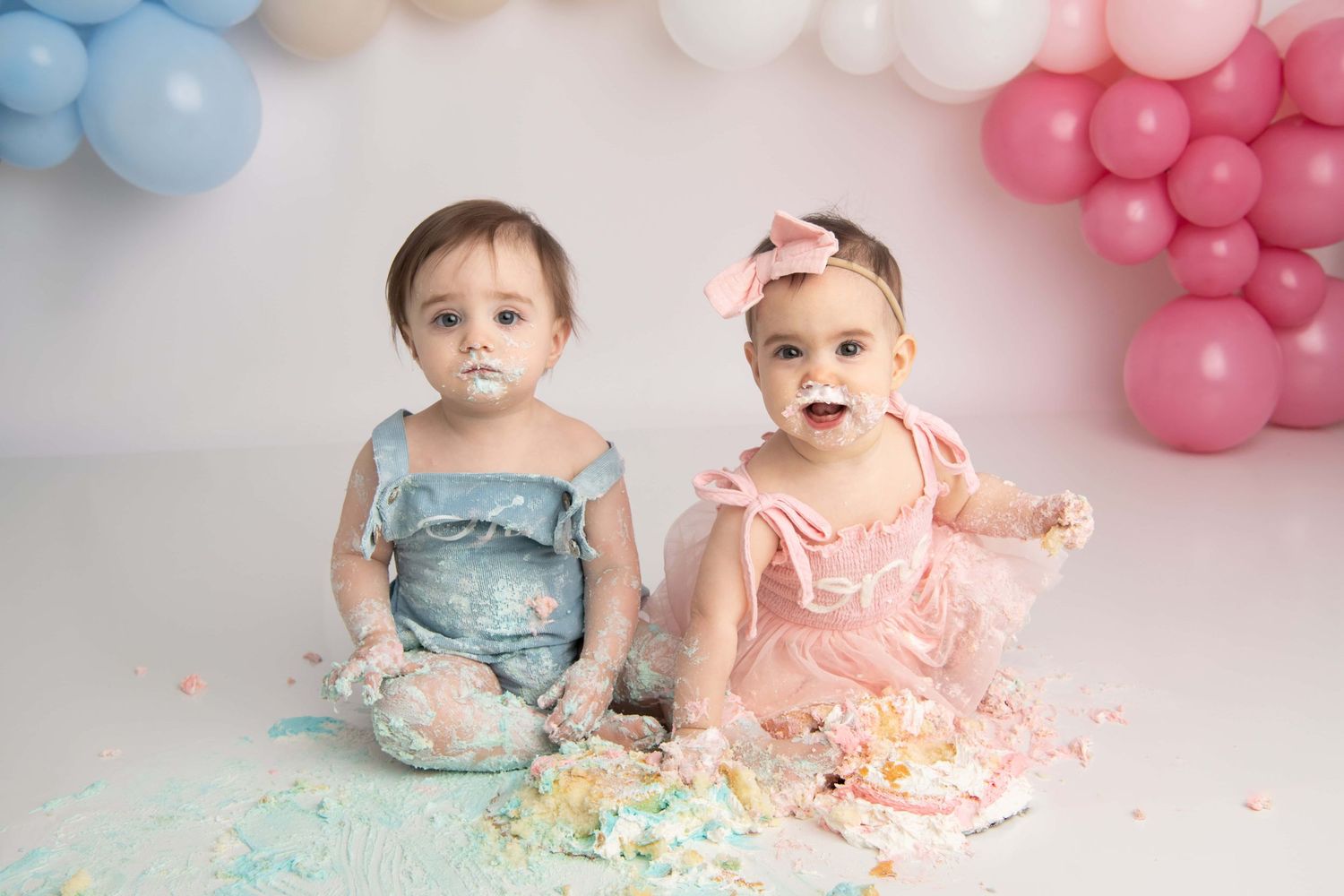 Twin one year olds smash pink and blue cakes for their cake smash portraits in Walla Walla.