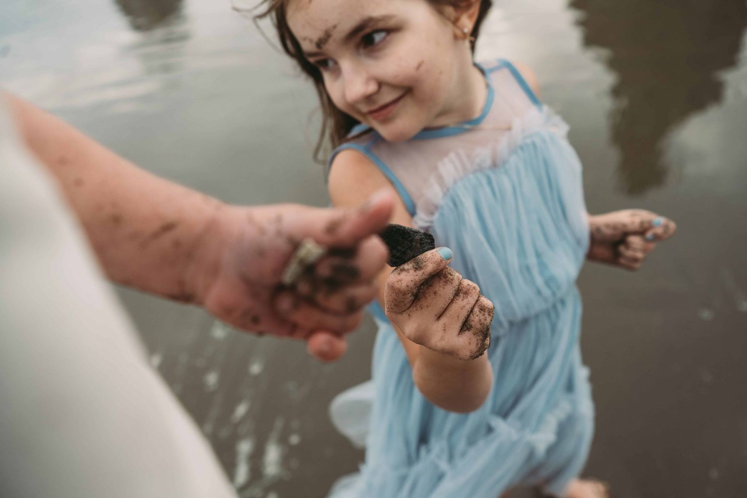 A detail image of two children holding rocks that they found at the beach.