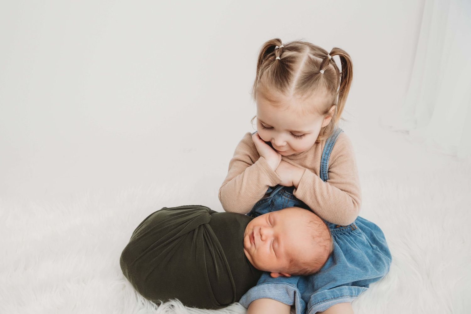A Walla Walla newborn photographer captures a toddler girl looking down at her newborn brother.