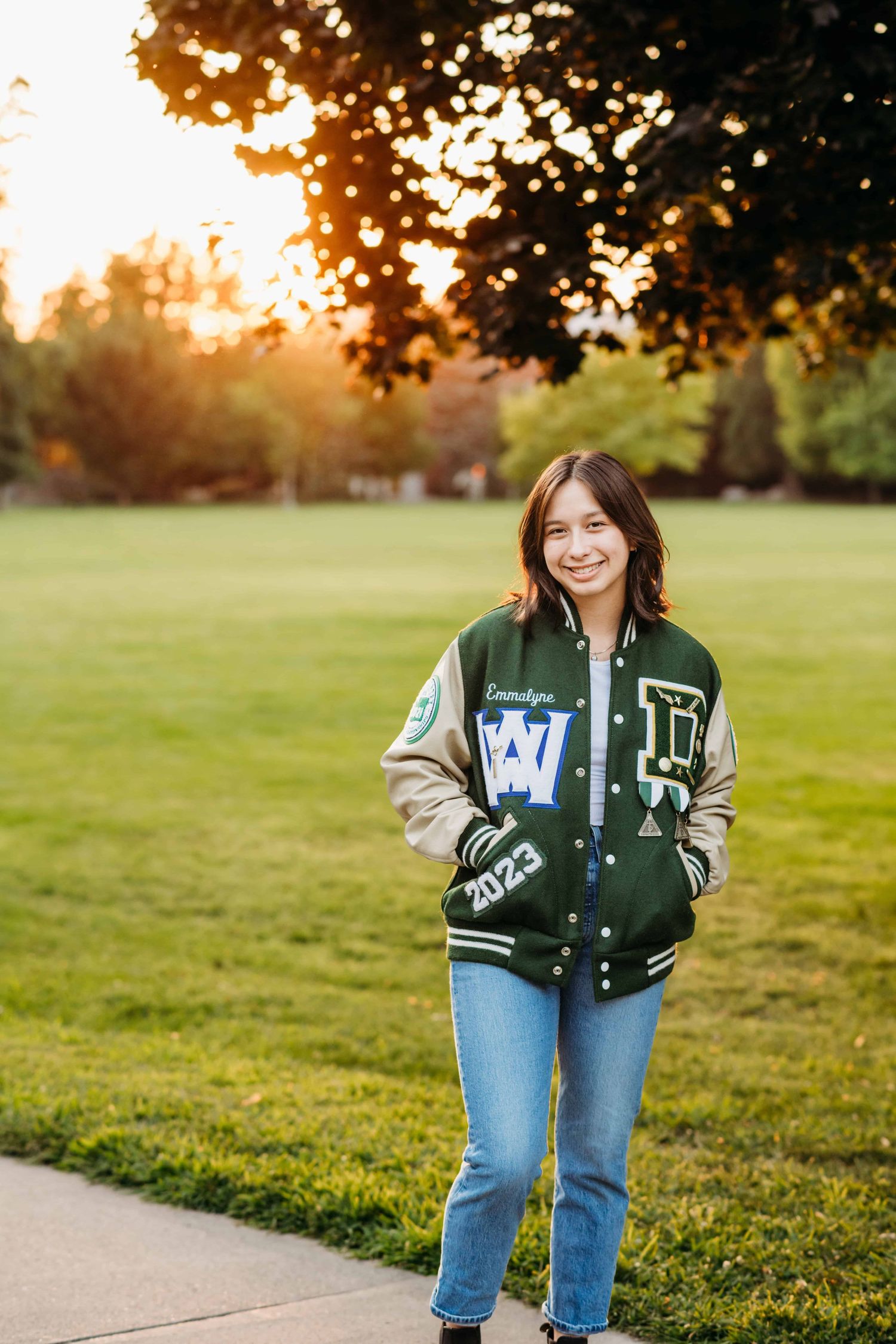 A senior wearing a jacket standing near a grassy field at Whitman College in Walla Walla.