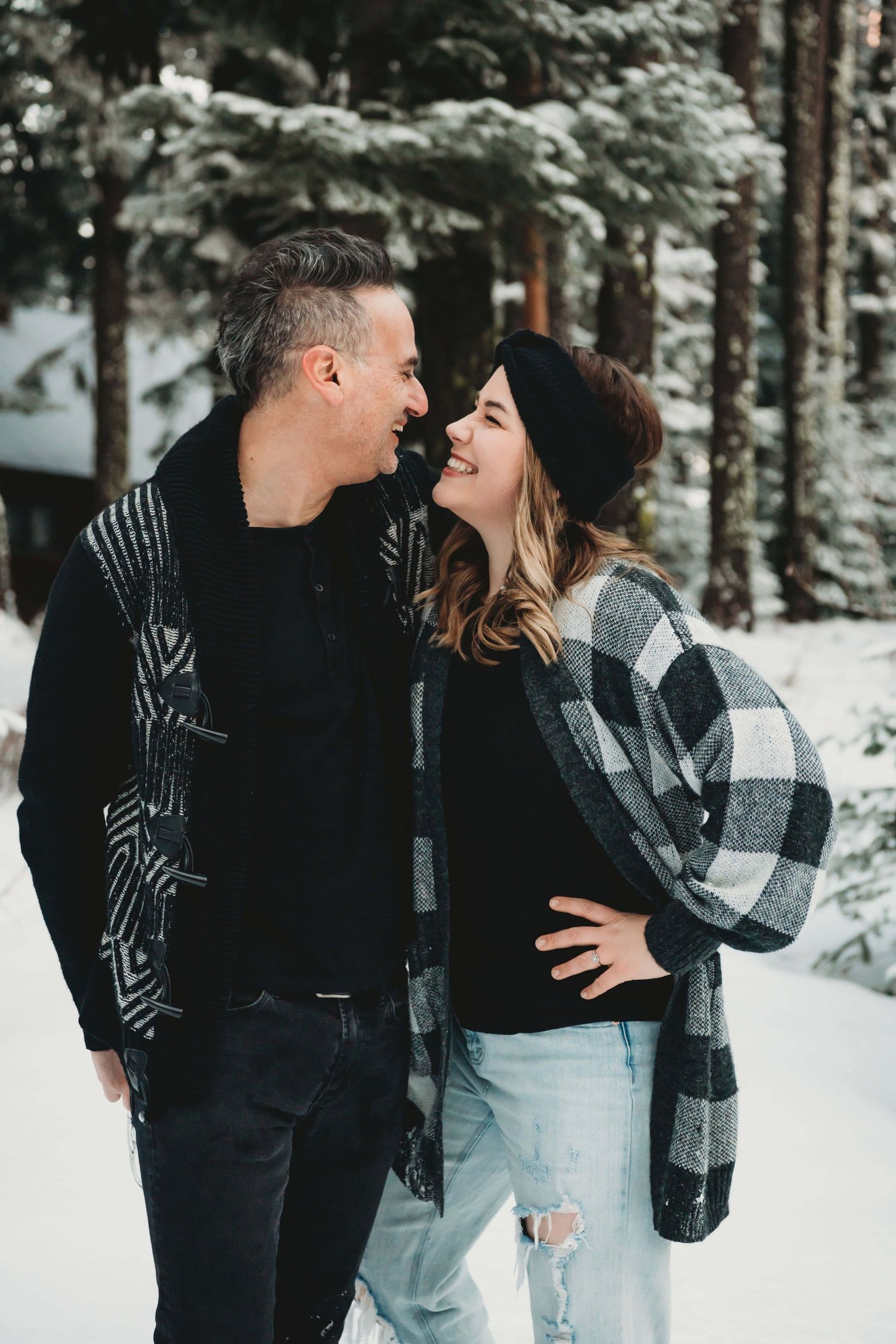 A couple looking at each other laughing in the snow.