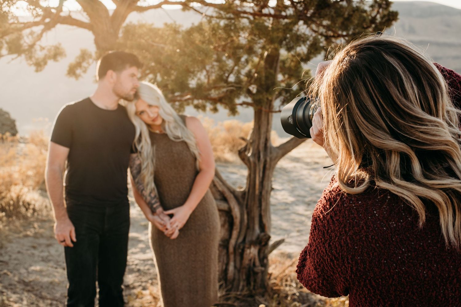A behind the scenes photo of Brittani, a Walla Walla photographer capturing a portrait of a couple during golden hour.