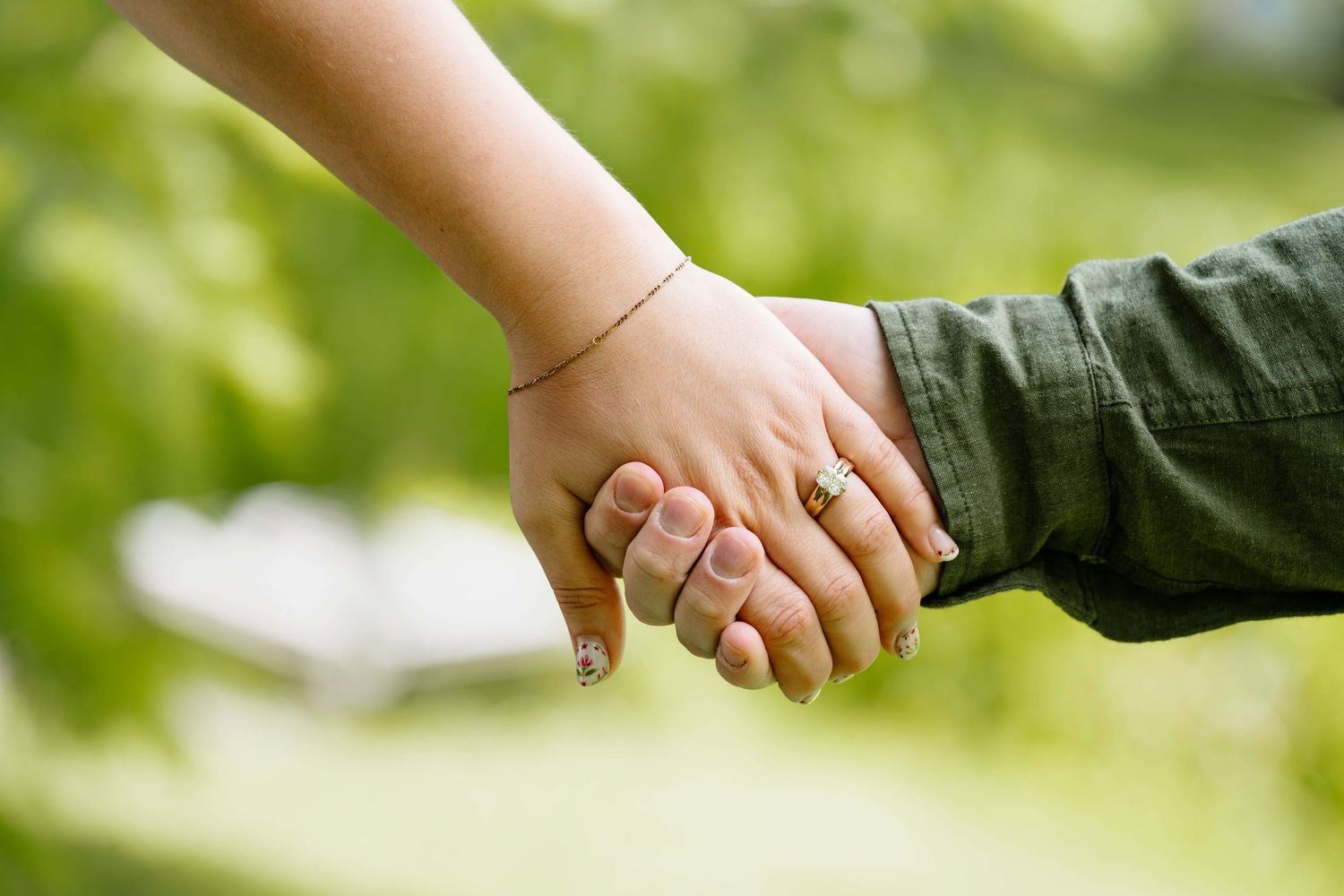 A close up of a couples hands to show off her new engagement ring just after he proposed.