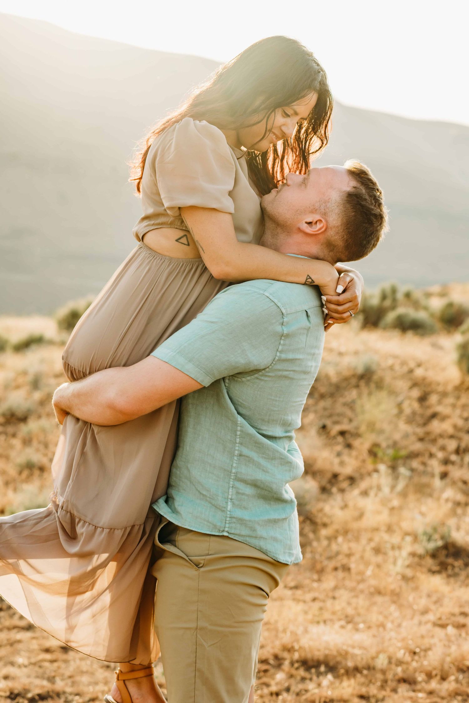 A couples portrait of a man picking up his girlfriend and smiling.