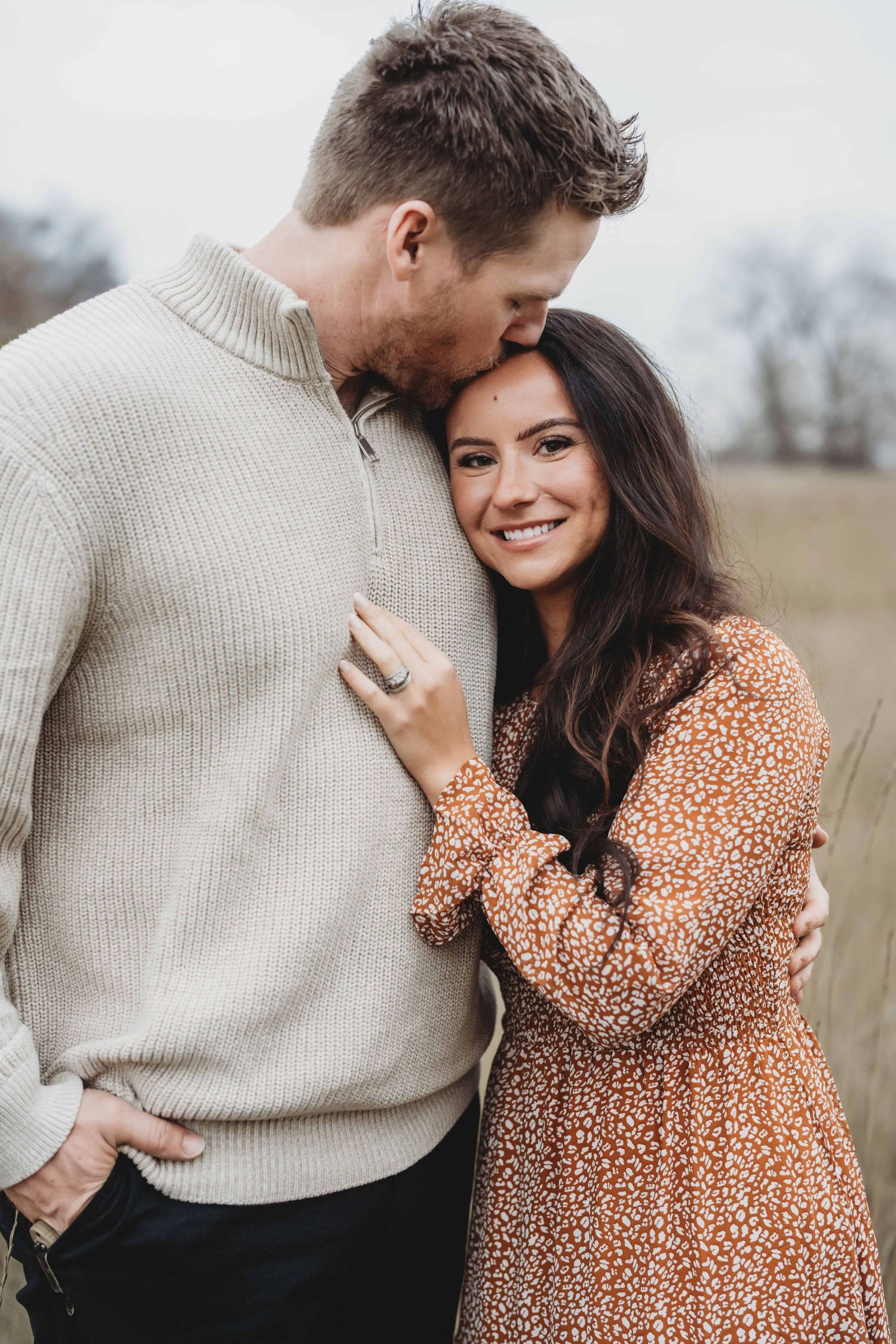 A man kissing his wife's forehead while she looks at the camera.