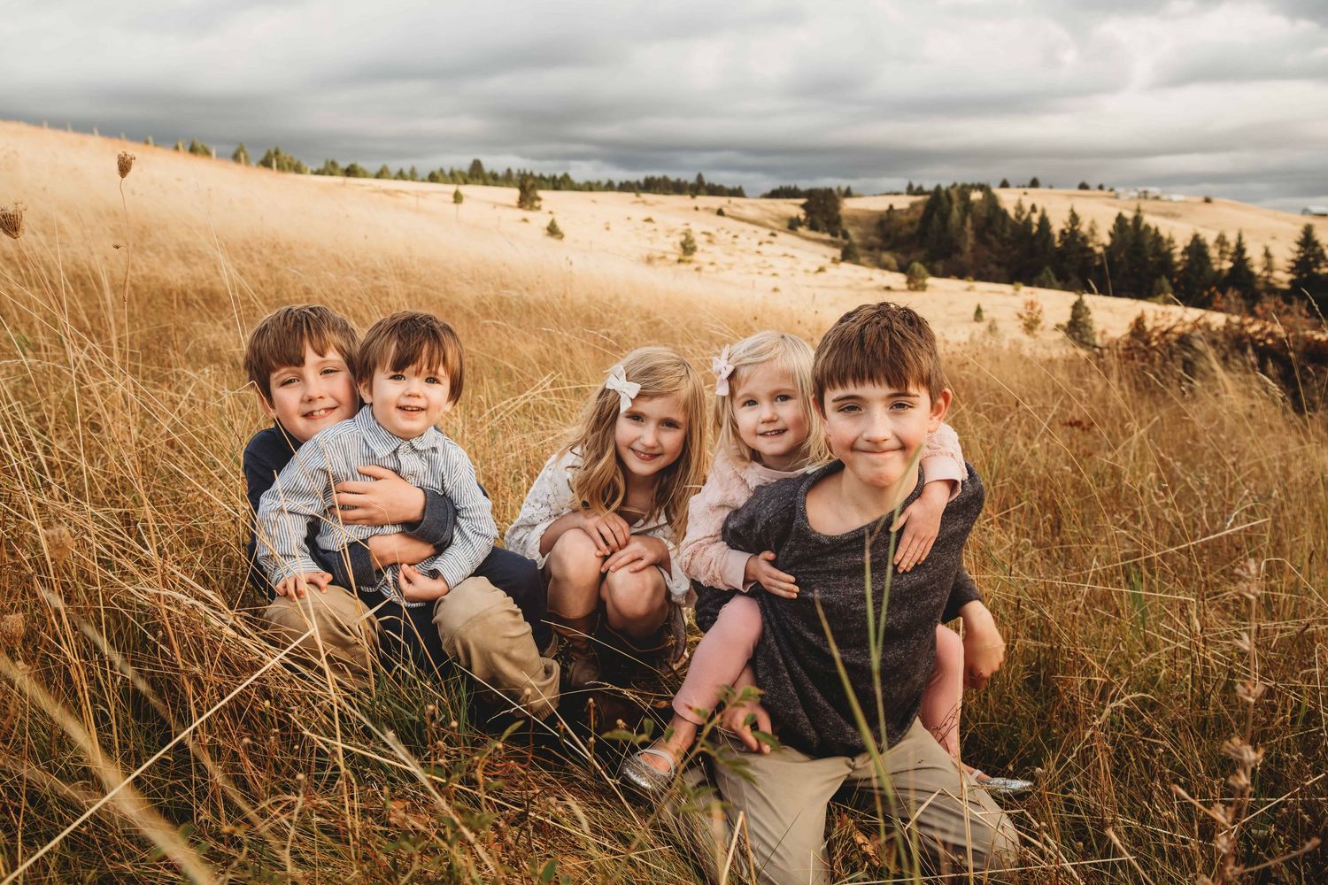 A Walla Walla photographer captures five children sitting in a large field during sunset.