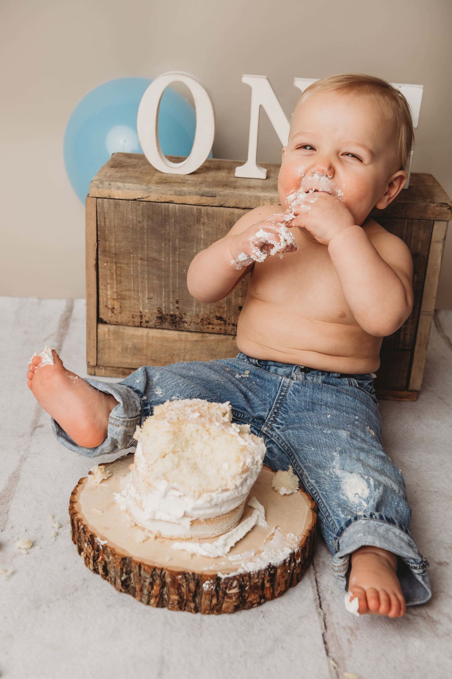 A one year old looks happy while he eats his cake for his first birthday.