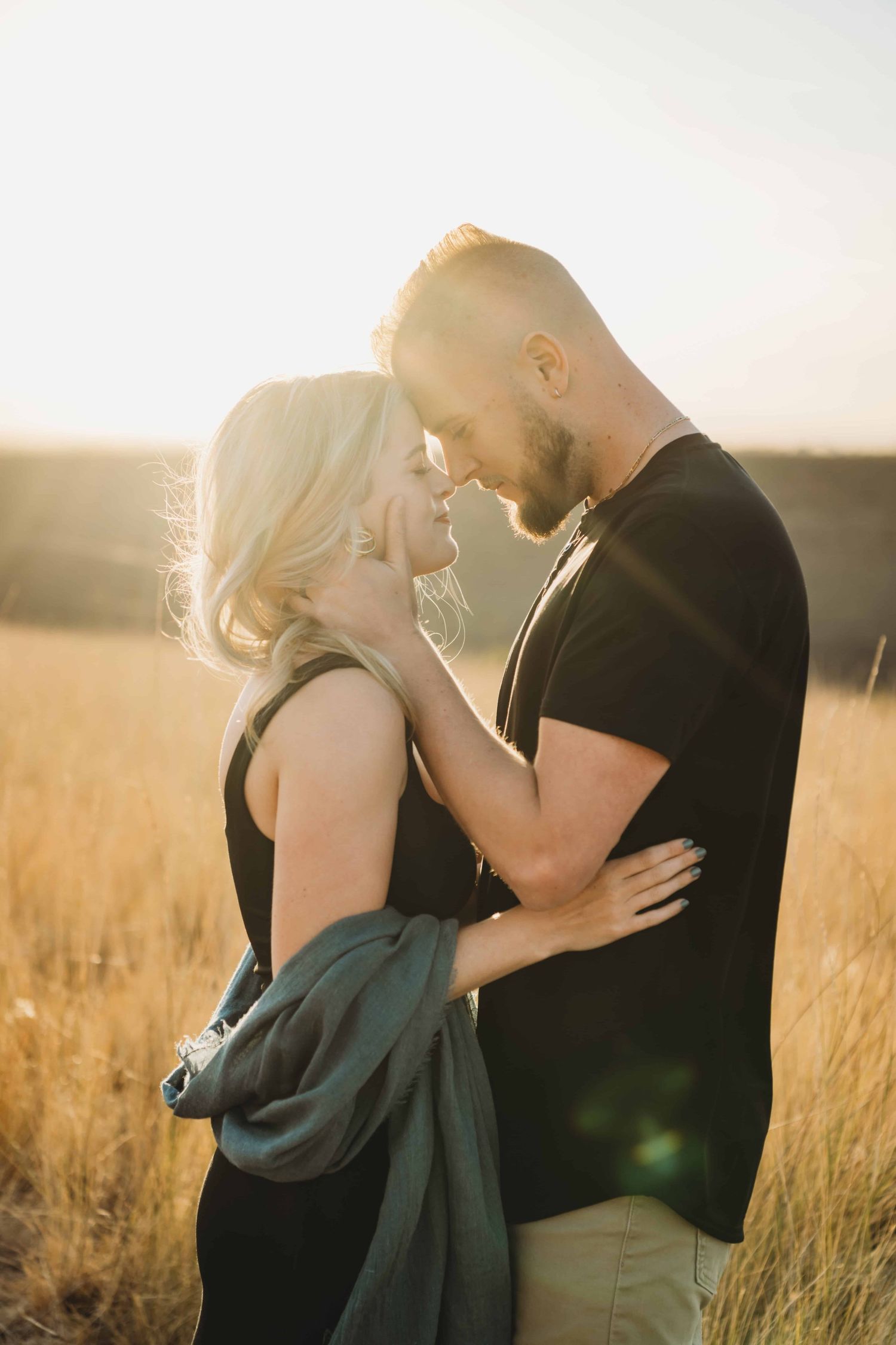 Couple embracing at golden hour in a grassy field during a Walla Walla couples photo session.