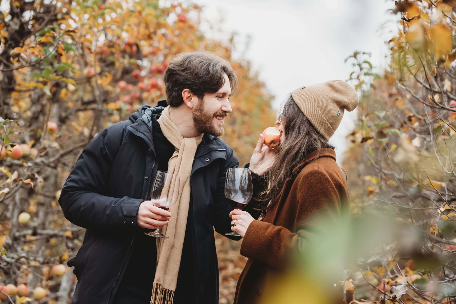A man giving his new fiancee a bite of an apple that he picked from a tree in an orchard, taken by a Walla Walla proposal photographer.