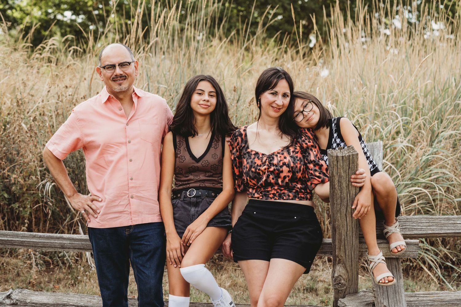Family portrait by a Walla Walla photographer showing parents and children posing together outdoors in tall grass.