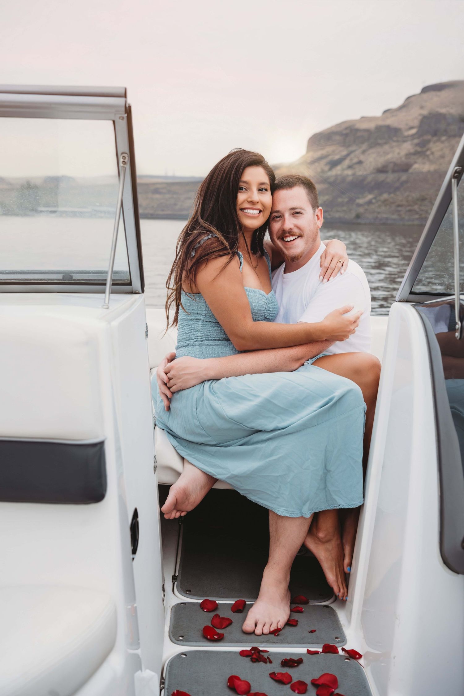 An engagement photo of a couple sitting together on their boat on the Columbia River.