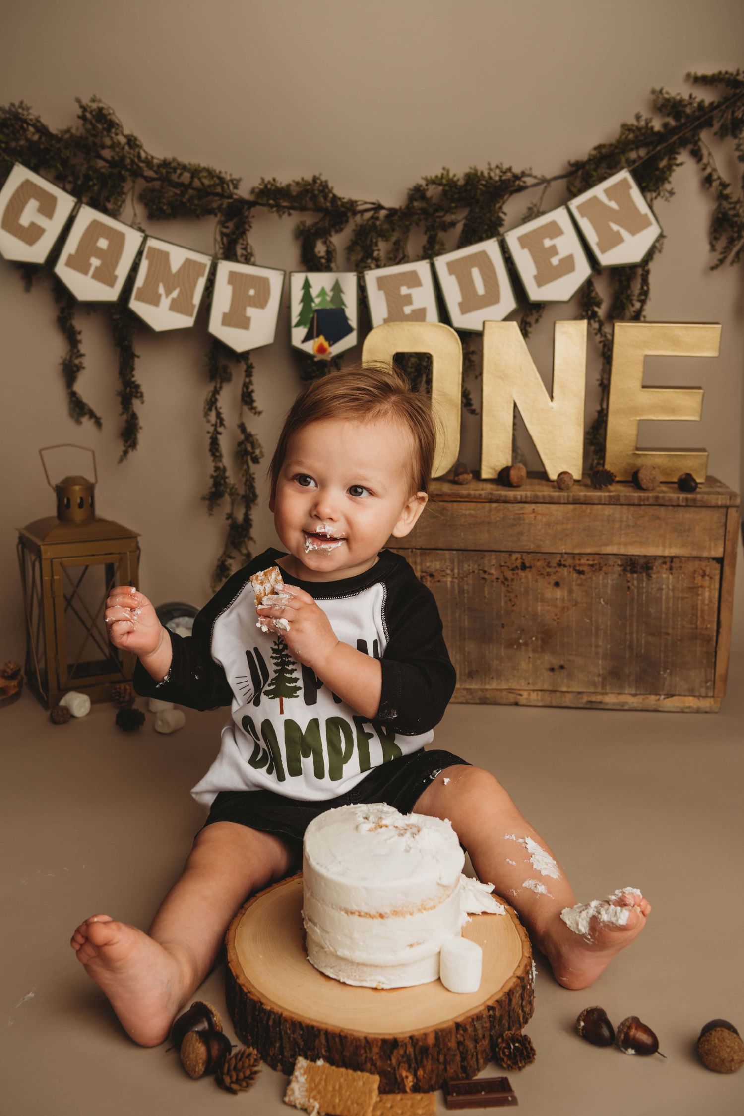 A cake smash portrait taken by a Walla Walla photographer of a one year old on a camping themed background.