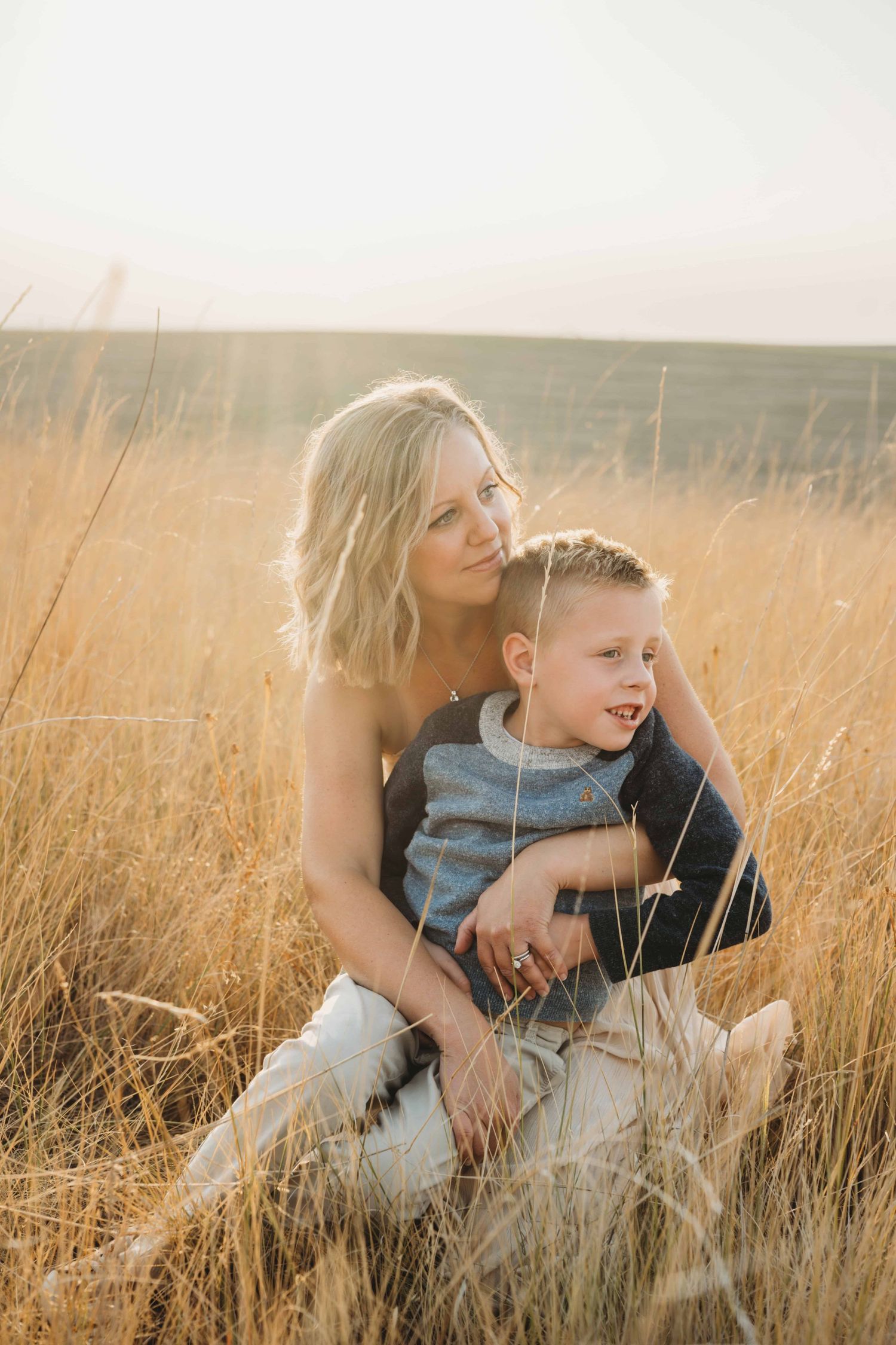 A mom sits in a field and looks off in the distance with her young son in Walla Walla.