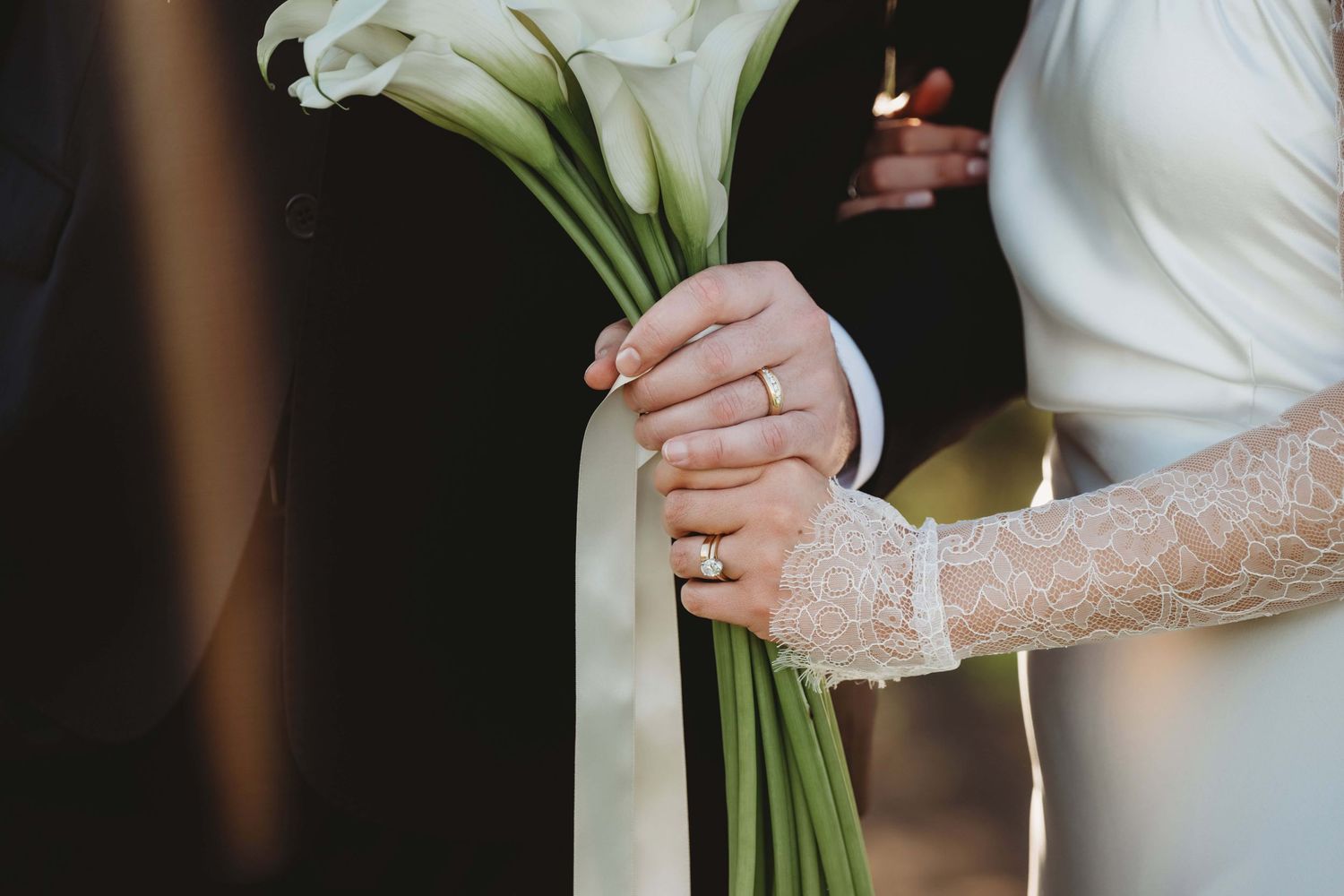 A close up of a bride and groom holding a bouquet of flowers.