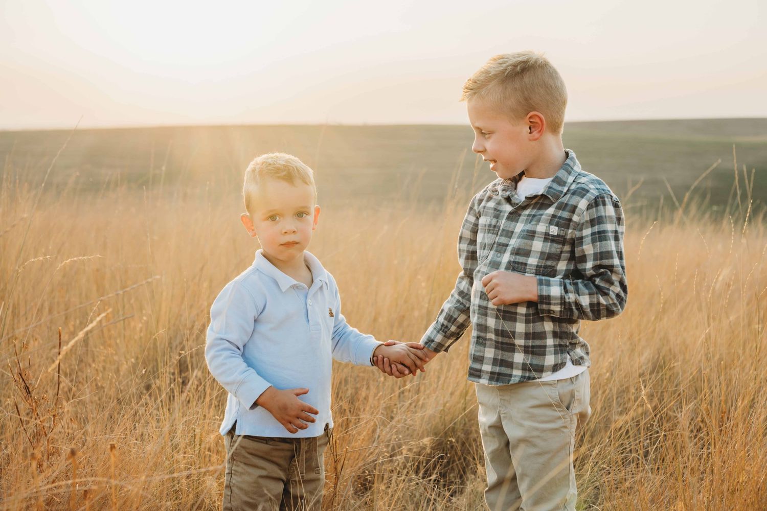A candid portrait of two children holding hands in a field at Bennington Lake in Walla Walla.
