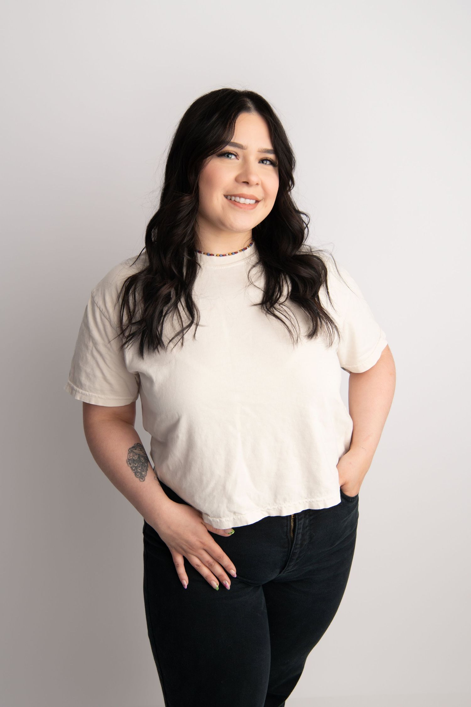 A classic headshot of a woman wearing black and white standing on a clean, white backdrop in studio.