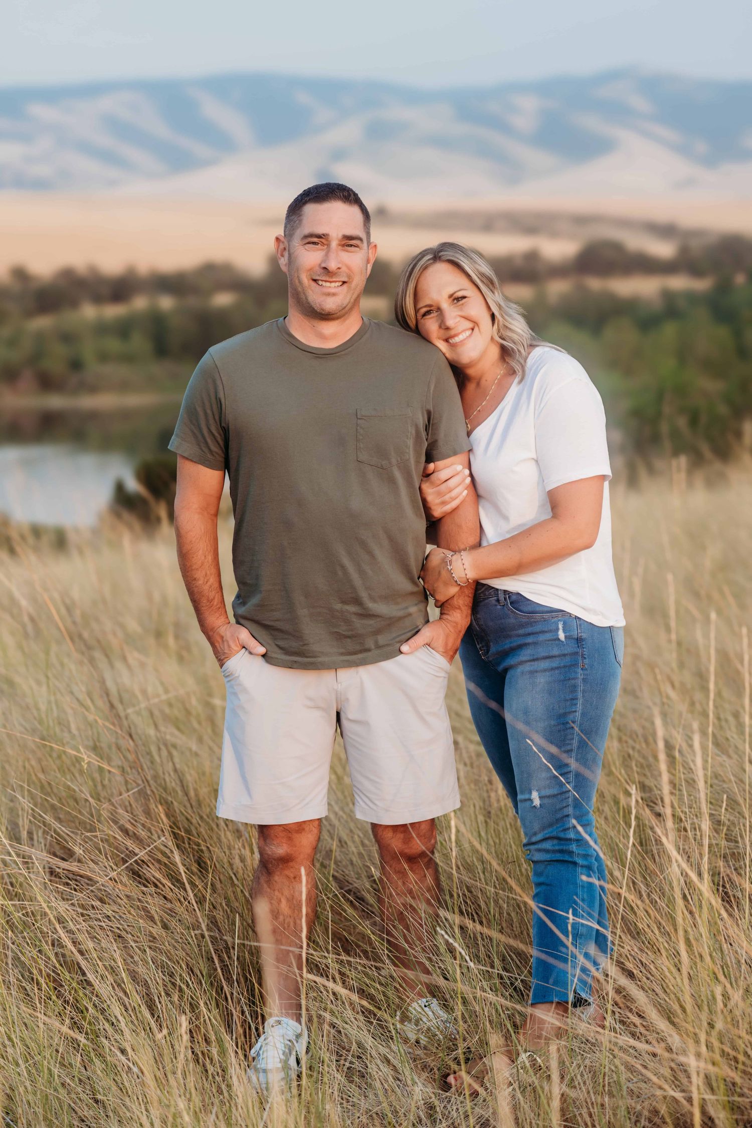 A casual portrait of a couple standing in a field overlooking Bennington Lake in Walla Walla.
