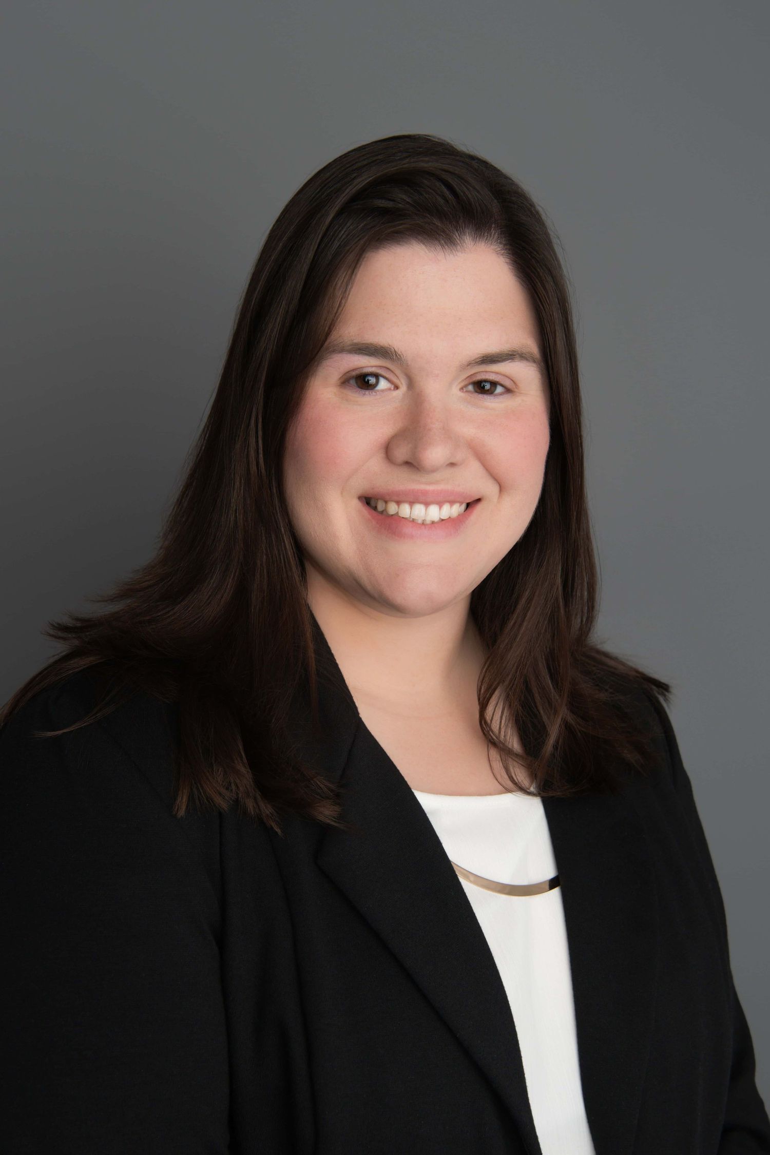 A woman smiling for a headshot on a gray backdrop in Walla Walla.
