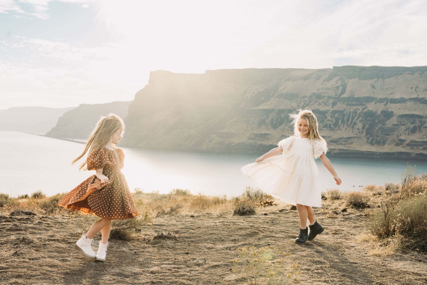 A portrait of two children wearing dresses spinning during golden hour with mountains in the background near Walla Walla.