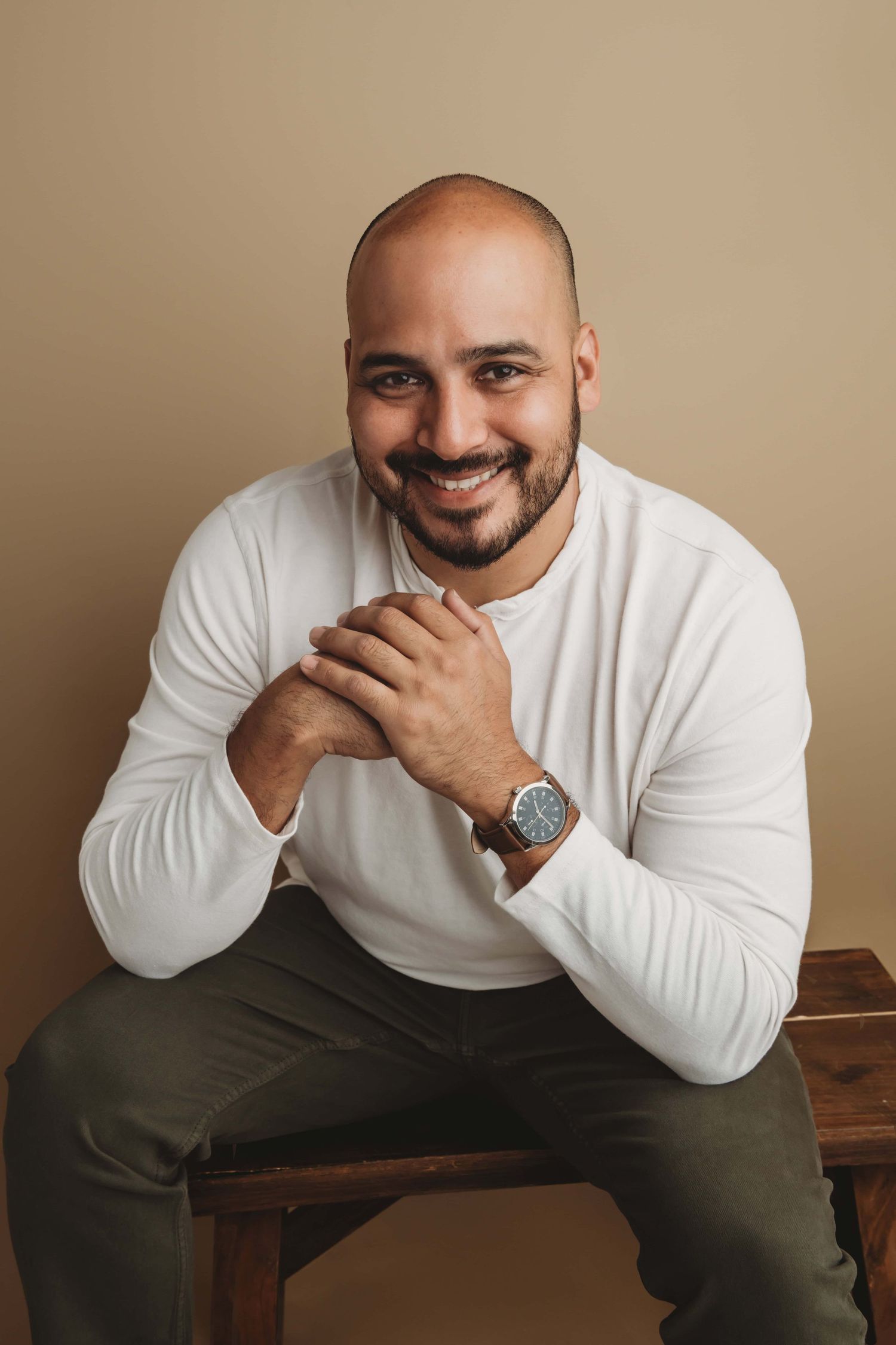 A Walla Walla headshot photographer captures a natural headshot of a man seated on a wooden bench in studio.