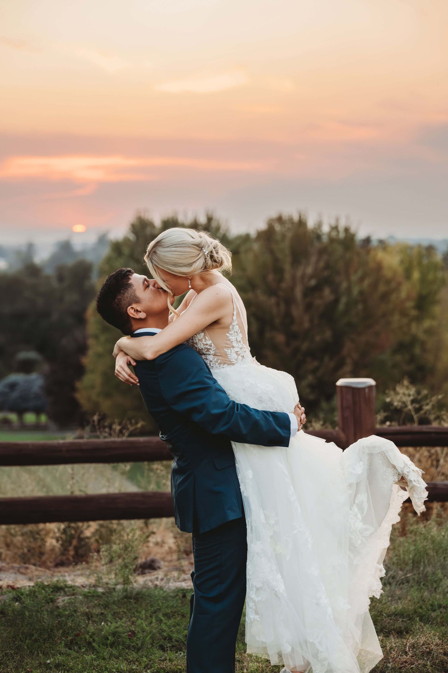 A groom picking up his bride and kissing her during sunset after their wedding reception at Yellow Hawk resort in Walla Walla.