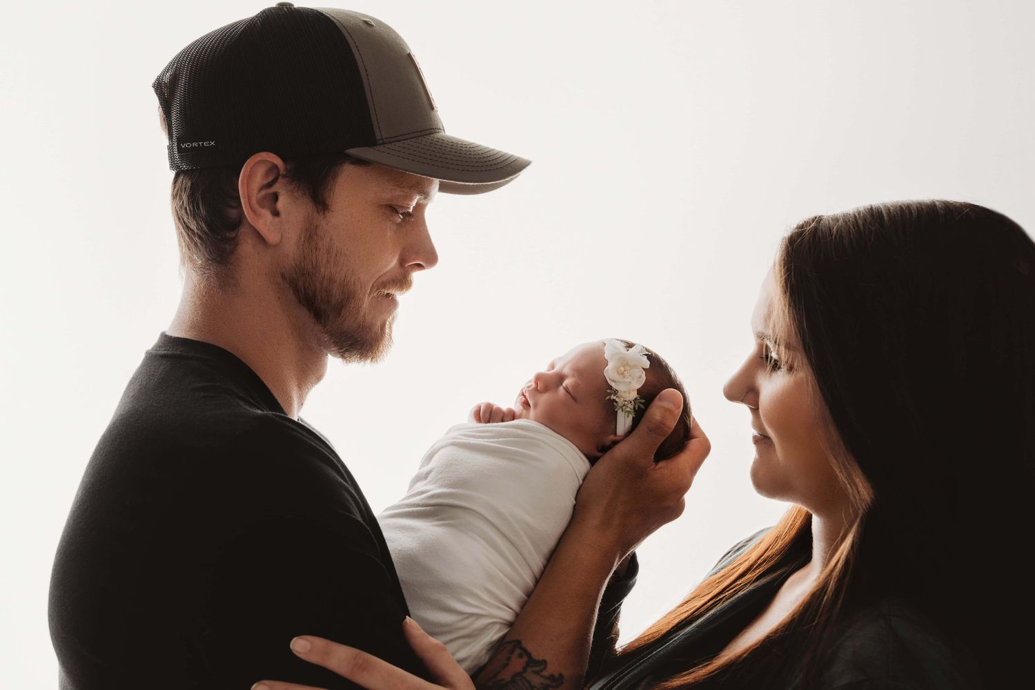 A backlit newborn portrait of a mother and father looking at their baby.