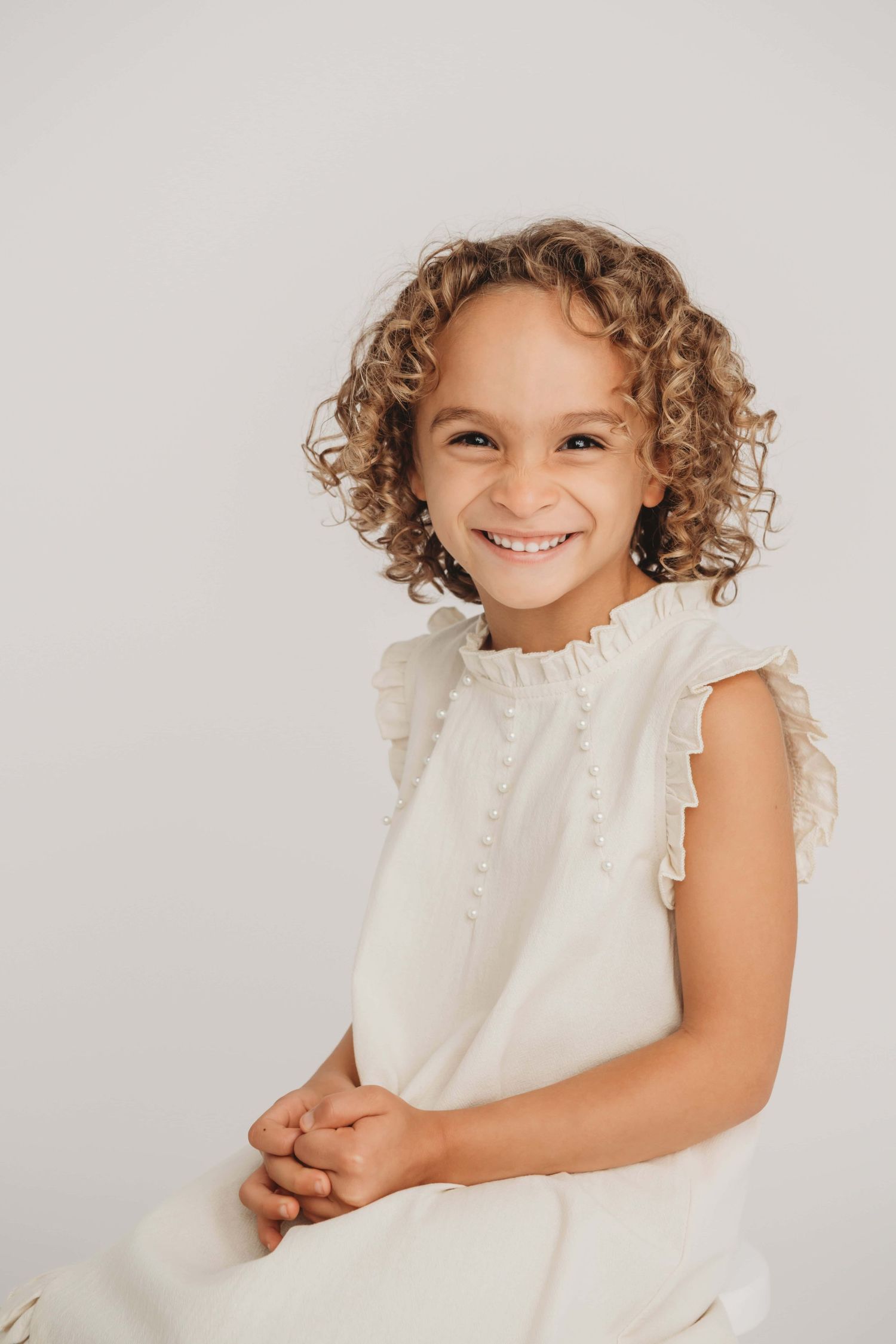 Child portrait by a Walla Walla photographer showing a smiling young girl with curly hair in a bright studio setting.