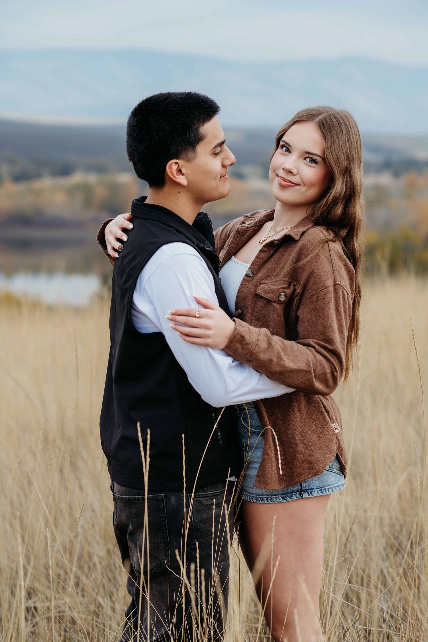Intimate engagement portrait of a couple hugging in an open field at golden hour, photographed by a Walla Walla couples photographer.