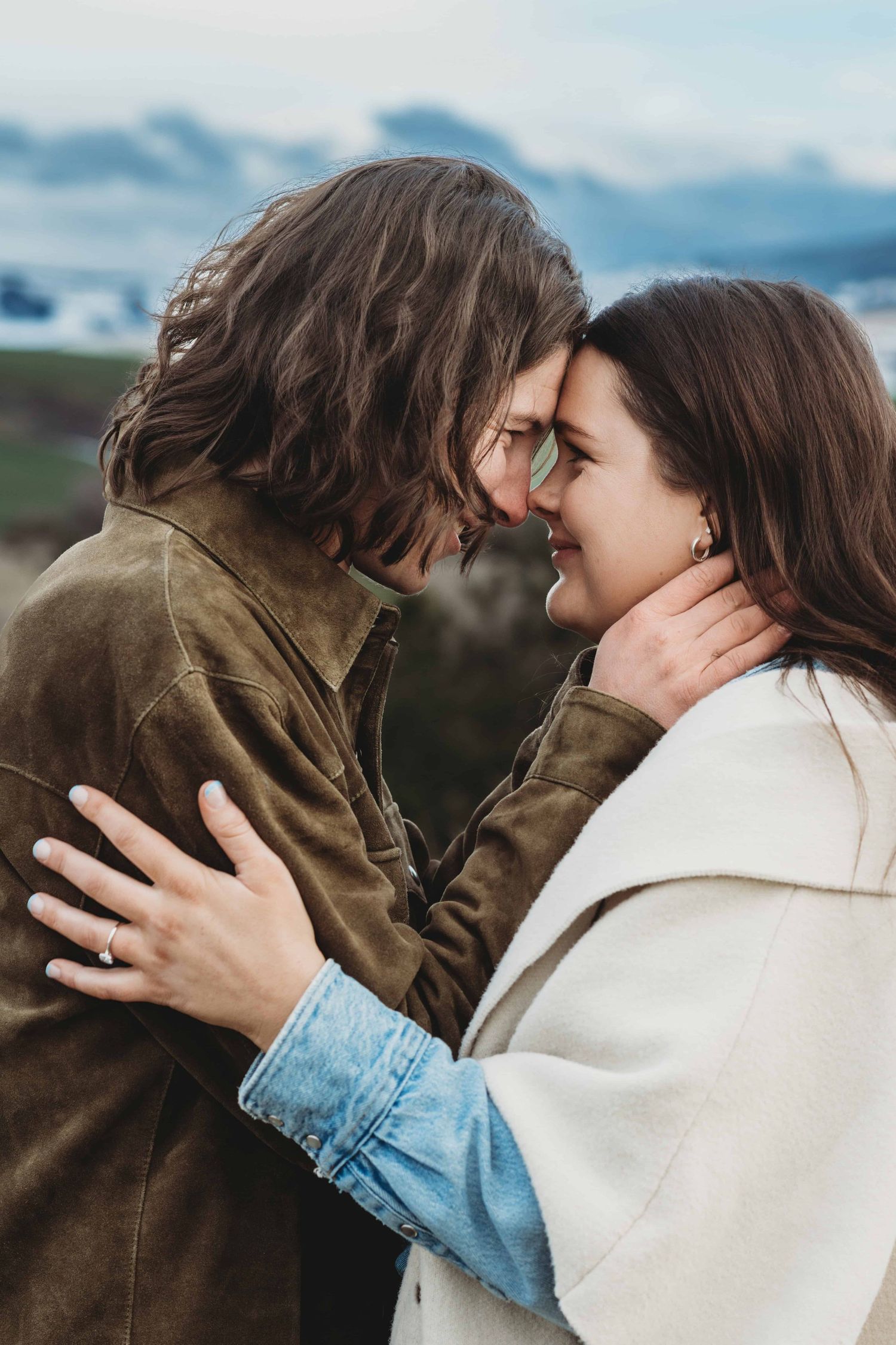 A newly engaged couple smiling with their faces close together.