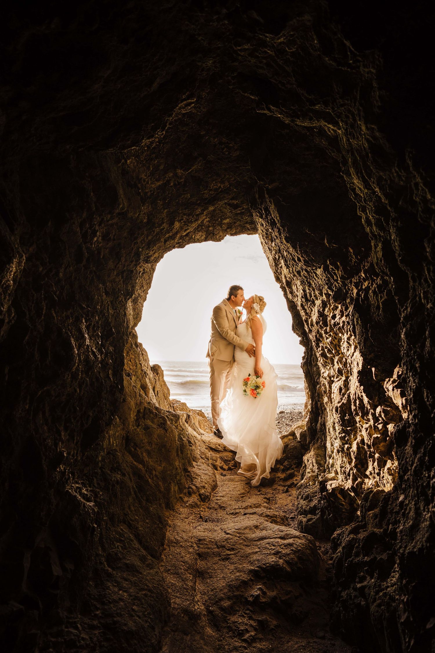 A couple standing at the entrance of a cave on the Oregon coast.