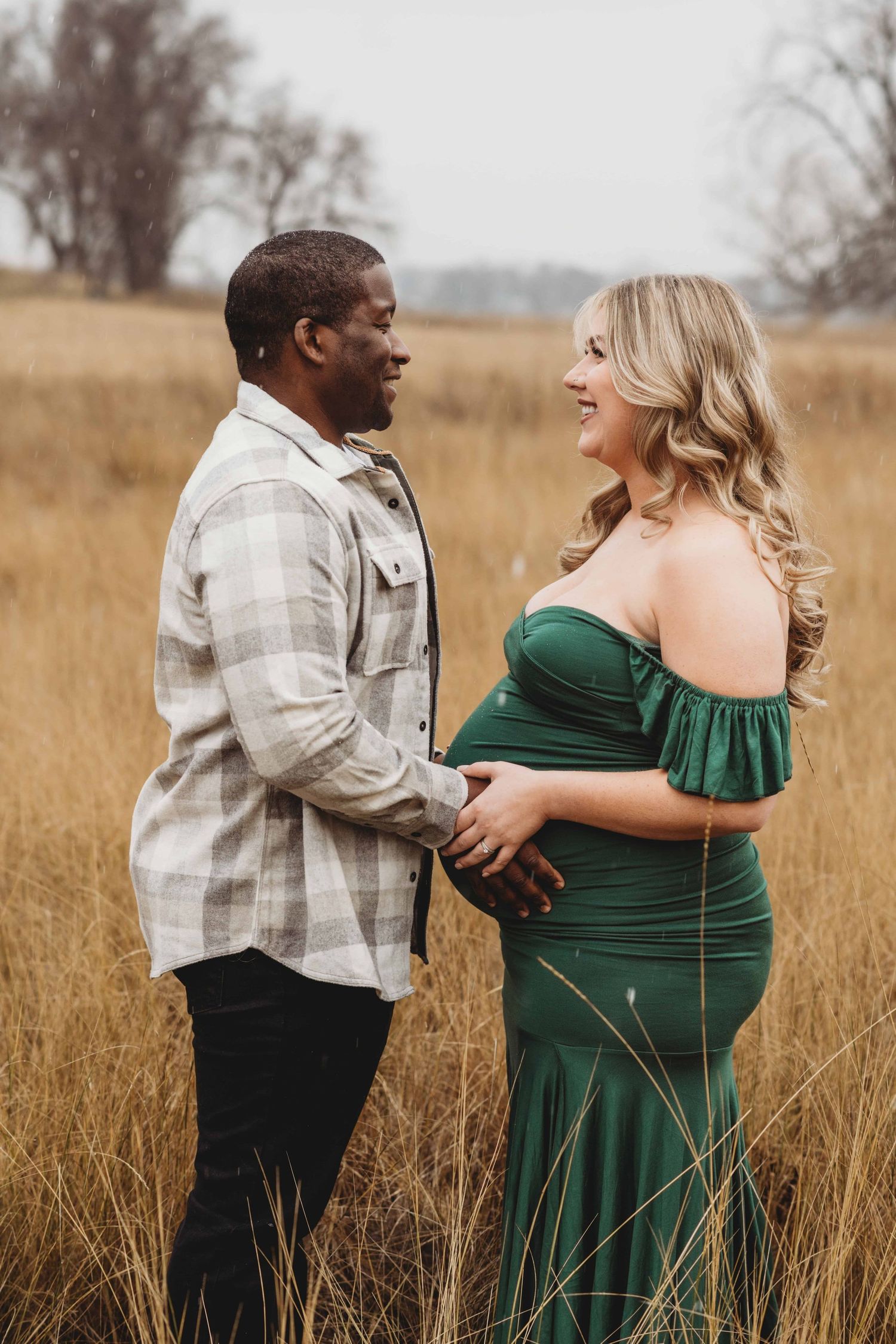 A Walla Walla maternity photographer captures a couple looking at each other with excitement while touching the baby bump.