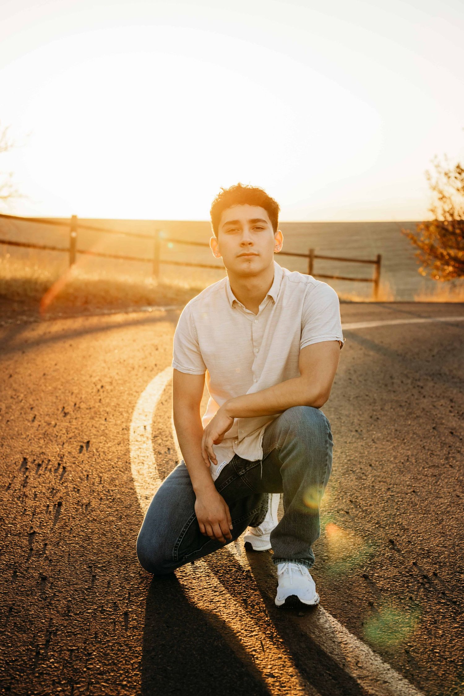 A senior portrait of a young man kneeling on the yellow stripe in the road at Bennington Lake in Walla Walla.